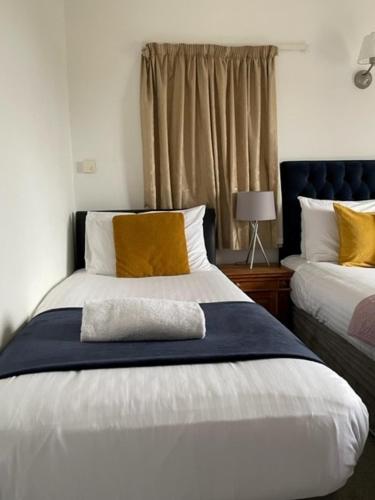 a bedroom with two beds with yellow and white pillows at The Calf Suite in Aberystwyth