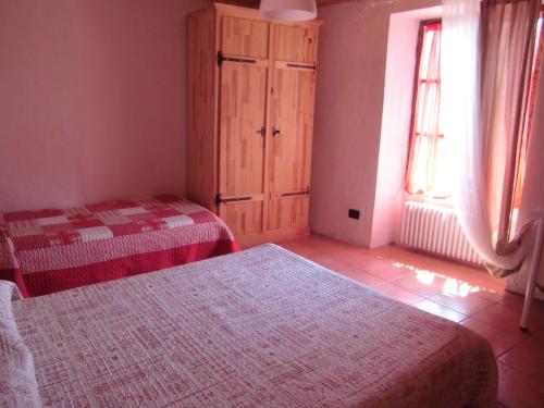 1 Schlafzimmer mit 2 Betten, einem Schrank und einem Fenster in der Unterkunft La Casa Antica in Pont-Saint-Martin