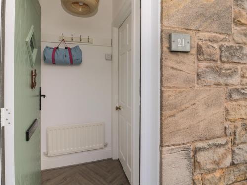 a hallway with a door and a stone wall at Cosy Cottage in Morpeth
