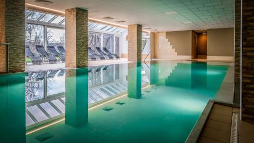 a swimming pool with blue water in a building at Silva Hotel Spa-Balmoral in Spa