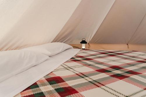a bed in a tent with a quilt on it at tendù family in Chiusanico