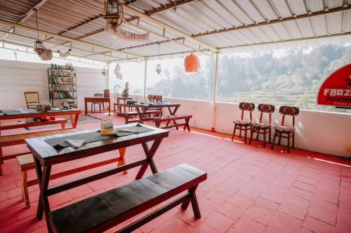 un restaurante con mesas y sillas y una gran ventana en Frozen Monks en Kodaikānāl