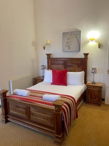 una camera da letto con un grande letto in legno con cuscini rossi di The Hay Suite ad Aberystwyth