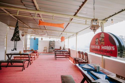 un restaurante con mesas y sillas en una habitación en Frozen Monks en Kodaikānāl
