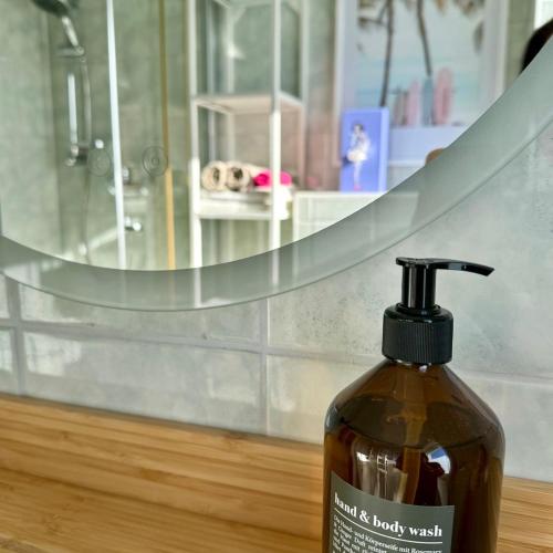 a bottle of liquid soap sitting on a table in front of a mirror at Pension Ostsee-Strand in Börgerende-Rethwisch
