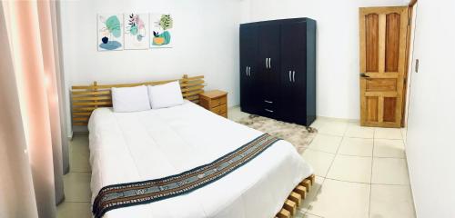 a bedroom with a white bed and a black cabinet at SAMAY, casa familiar en el valle sagrado in Calca