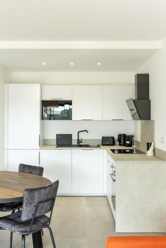 une cuisine avec des armoires blanches et une table et des chaises dans l'établissement Flaubert 17 - Domaine d'Arca - 4 pers, à Porto-Vecchio