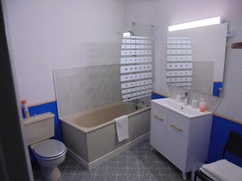 a bathroom with a tub and a toilet and a sink at Hotel De La Gare in Montluçon