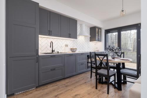 a kitchen with gray cabinets and a table with chairs at Apartment in Krakow with parking and balcony by Renters in Modlnica