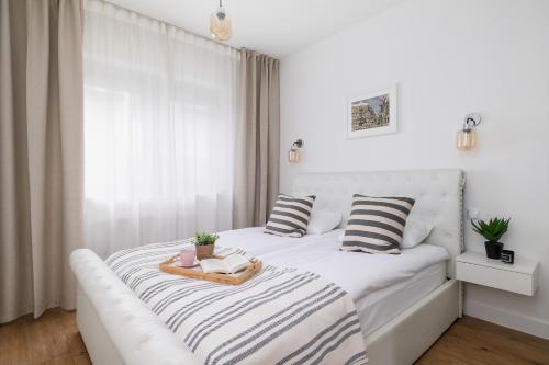 a white bedroom with a white bed with striped pillows at Apartment in Krakow with parking and balcony by Renters in Modlnica