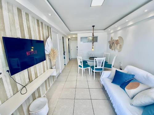 un soggiorno con divano blu e tavolo di Apartamentos no Condomínio Beach Village Fortaleza - Praia do Futuro - Por CasAmarInn a Fortaleza