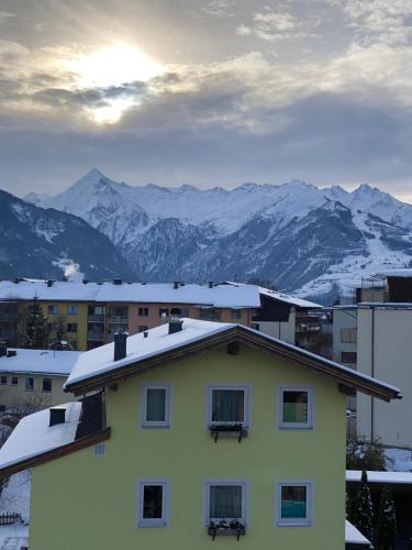 a house with snow on the roof with mountains in the background at Marina Alpen Haus in Zell am See