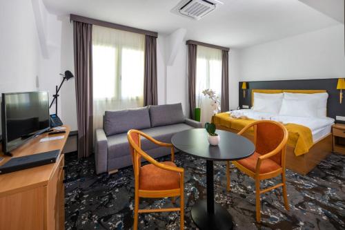 a hotel room with a bed and a couch and a table at Zsóry Liget Hotel & Spa Superior in Mezőkövesd