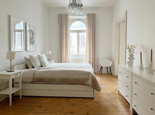 a white bedroom with a bed and a window at Lägenhet i centrala Stockholm in Stockholm