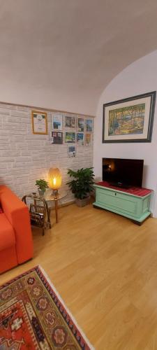sala de estar con sofá naranja y TV de pantalla plana en Suite dei Doria, en Dolceacqua