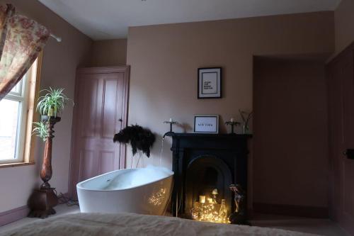a bathroom with a bath tub next to a fireplace at Victorian Farrar Cottage in York