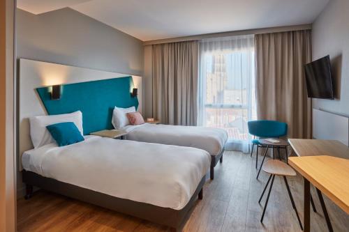 um quarto de hotel com duas camas e uma secretária em Aparthotel Adagio Heidelberg em Heidelberg
