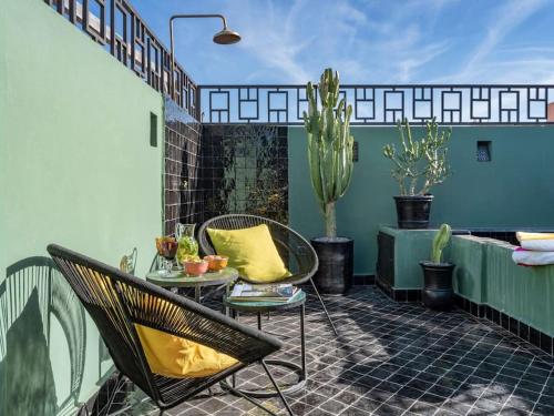 a patio with two chairs and a table and cactus at Riad Secret Garden Hideaway (privative) in Marrakesh