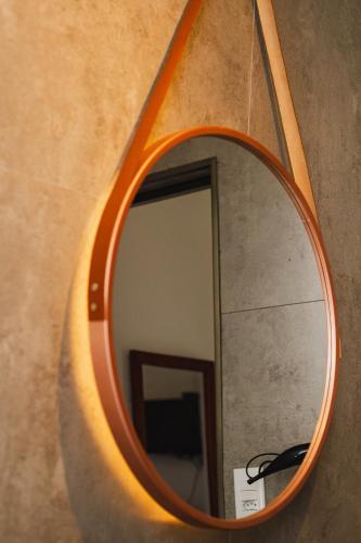 a mirror with an orange frame hanging on a wall at Quinta da Bocaina in Amparo