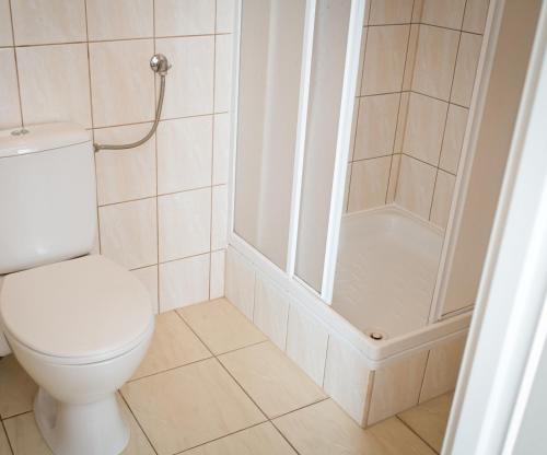 La salle de bains blanche est pourvue d'une douche et de toilettes. dans l'établissement Hotel Eden, à Rzeszów