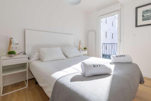 a white bedroom with two beds and a window at Egona - Martinenea in Zarautz