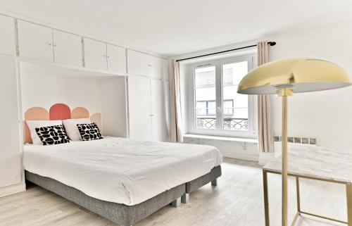 une chambre blanche avec un grand lit et une fenêtre dans l'établissement Appartement 2 pieces #TourEIffel #Invalides, à Paris
