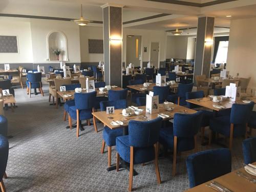 a dining room with wooden tables and blue chairs at Cumberland Hotel in Scarborough