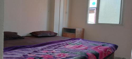 a bedroom with a bed with a purple blanket at Shree maya home stay in Ujjain