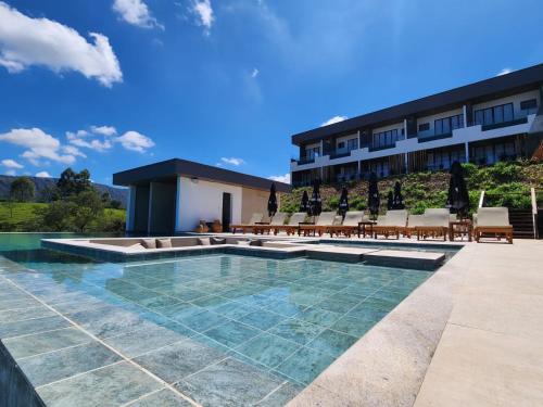 a resort with a pool and chairs and a building at Serrano Exclusive in Tiradentes