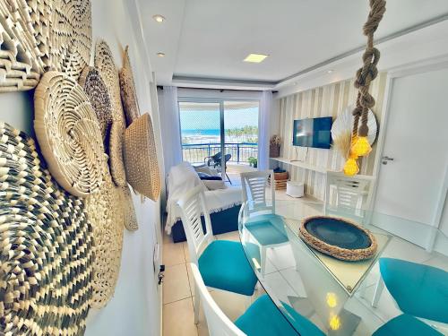 a living room with a glass table and blue chairs at Apartamentos no Condomínio Beach Village Fortaleza - Praia do Futuro - Por CasAmarInn in Fortaleza