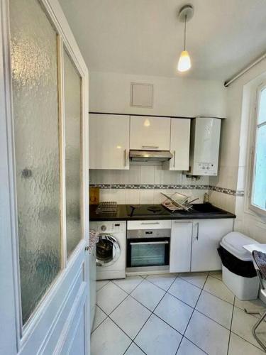 Elle comprend une petite cuisine avec des placards blancs et une fenêtre. dans l'établissement Beau 3P en plein cœur du 15eme Proche de Beaugrenelle et de la Tour Eiffel. ., à Paris