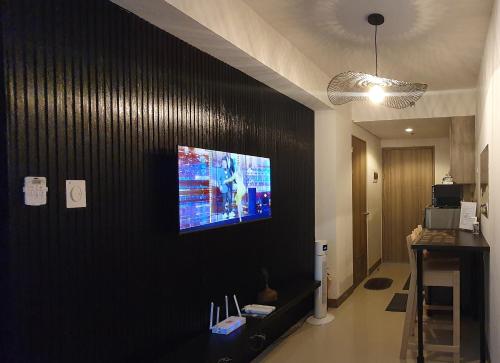 a living room with a tv on a black wall at C Place - Capsule B in Manila
