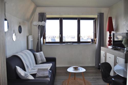 sala de estar con sofá, silla y ventana en Mer et Soleil à Blonville sur mer/ Deauville, en Blonville-sur-Mer