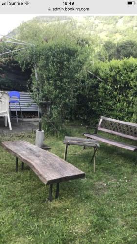 a picnic table and a bench in the grass at Appartamento in Attico in Poschiavo