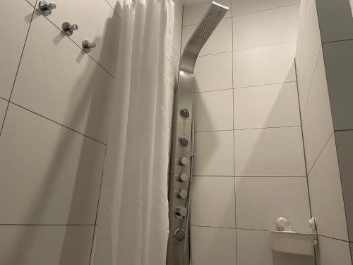 グリヴィツェにあるThe Loft Premium Gliwiceの白いシャワーカーテンとナイフが置かれたシャワー