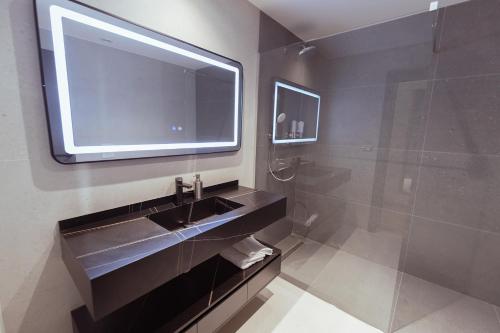 baño con lavabo y TV en la pared en La Terrazza Hotel & Restaurant, en Hani i Elezit