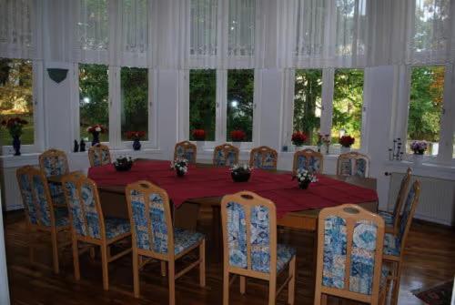 uma sala de jantar com mesa, cadeiras e janelas em Ferienvilla Teufelsmauer em Cattenstedt