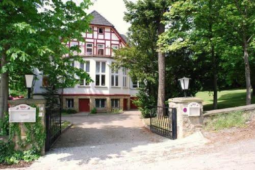uma grande casa rosa e branca com um portão em Ferienvilla Teufelsmauer em Cattenstedt