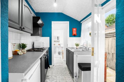 a kitchen with blue walls and white cabinets and a sink at Beautiful 3 Bed House Close to City Centre - Top Rated - Netflix - WIFI - Smart TV - 17ML in Birmingham
