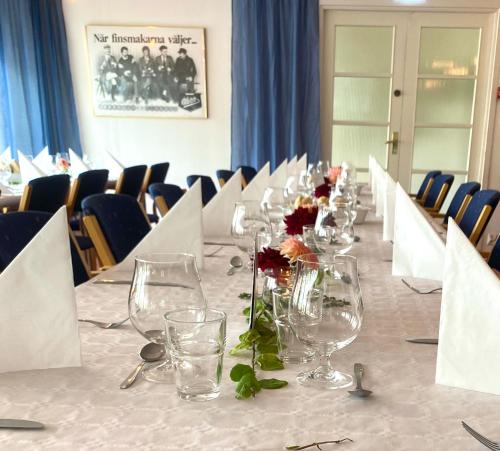 Gullringens Värdshus & hotell في Gullringen: طاولة طويلة مع كؤوس النبيذ والزهور عليها