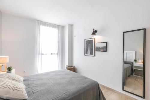 a white bedroom with a bed and a mirror at The Orbit Apartments in Barcelona