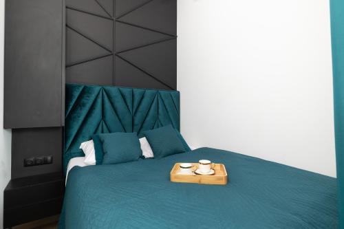 a bedroom with a green bed with a wooden tray on it at Modern Apartments with Swimming Pool in Hanza Tower by Renters in Szczecin
