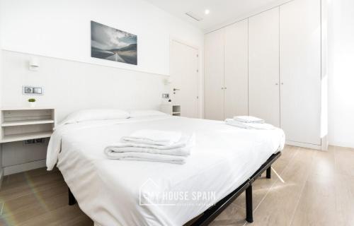 Un dormitorio blanco con una cama con sábanas blancas. en MyHouseSpain - Salustio Apartments, en Gijón