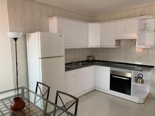 uma cozinha com electrodomésticos brancos e uma mesa e cadeiras em Apartamentos Bellavista Gomera em Playa de Santiago