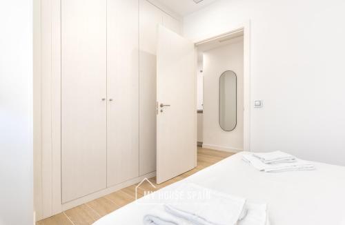 - une chambre blanche avec un lit et un miroir dans l'établissement MyHouseSpain - Salustio Apartments, à Gijón