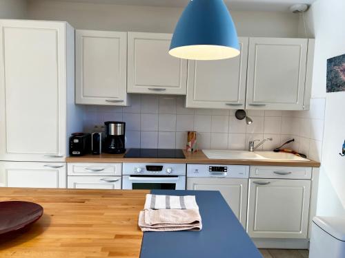 a kitchen with white cabinets and a blue pendant light at COC - Basse Mer in Wissant