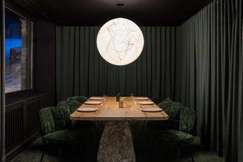 a table in a restaurant with green chairs and a light at Hotel Annapurna in Courchevel