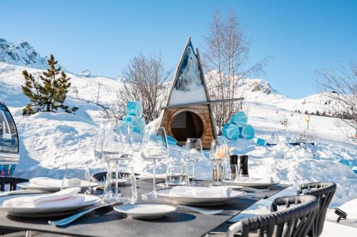 a table with glasses and a house in the snow at Hotel Annapurna in Courchevel