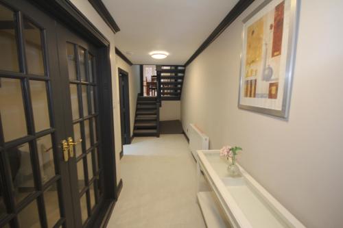 un couloir avec une porte et un escalier orné d'un vase de fleurs dans l'établissement Harrow Field Place, à Harrow on the Hill