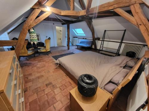 sypialnia z dużym łóżkiem w pokoju z drewnianymi belkami stropowymi w obiekcie Les Oiseaux de Passage w mieście Escolives-Sainte-Camille